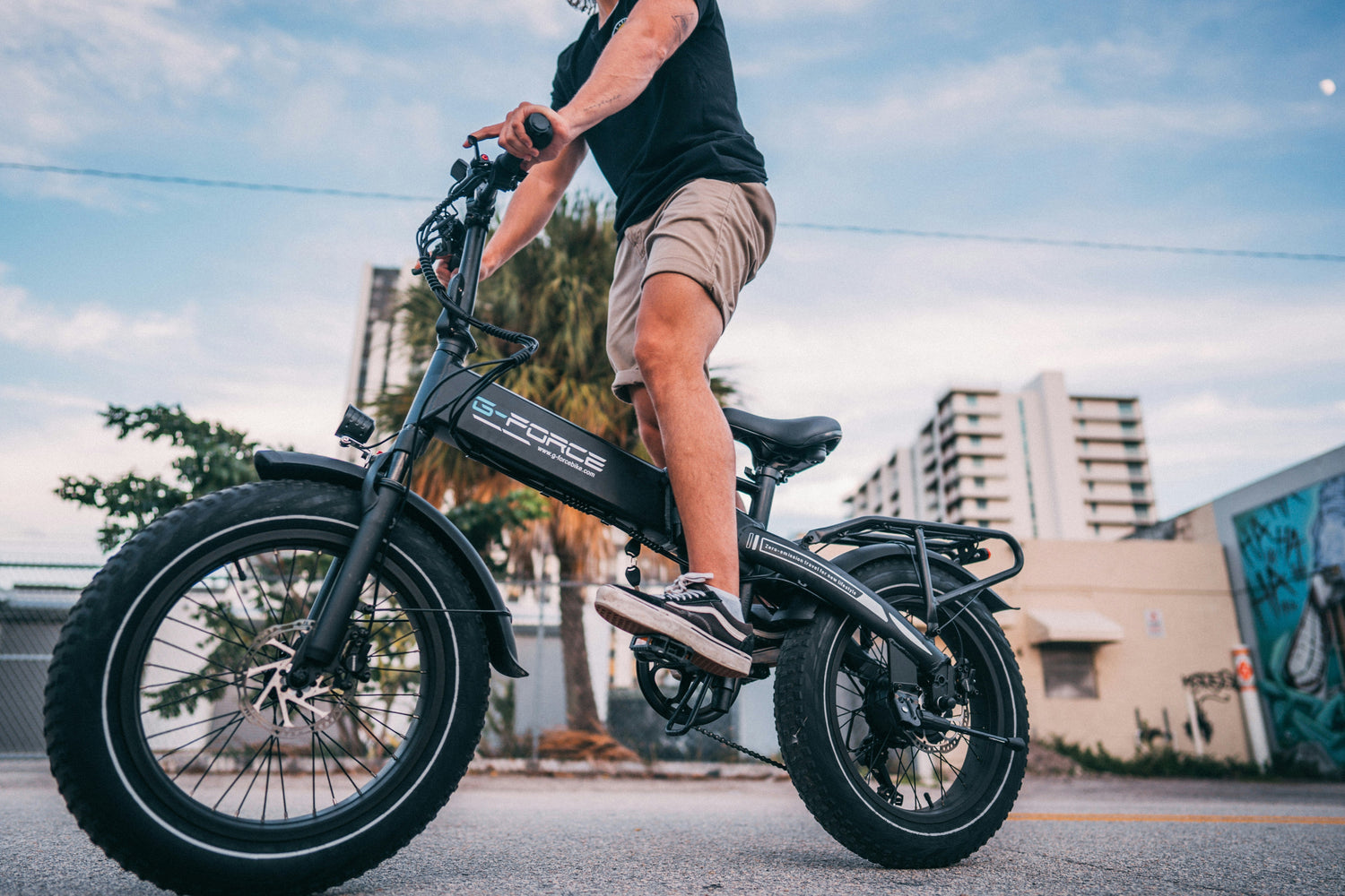 Man riding a black G-Force electric bike on a city street — showcasing a modern fat-tyre e-bike ideal for UK urban and off-road cycling.