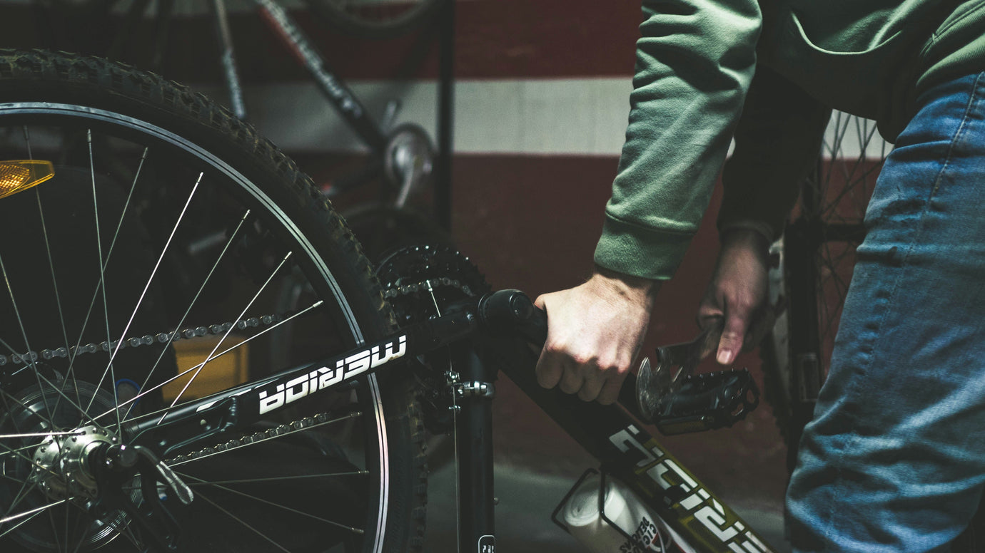 Cyclist adjusting pedals on a mountain bike in a local bike shop workshop.
