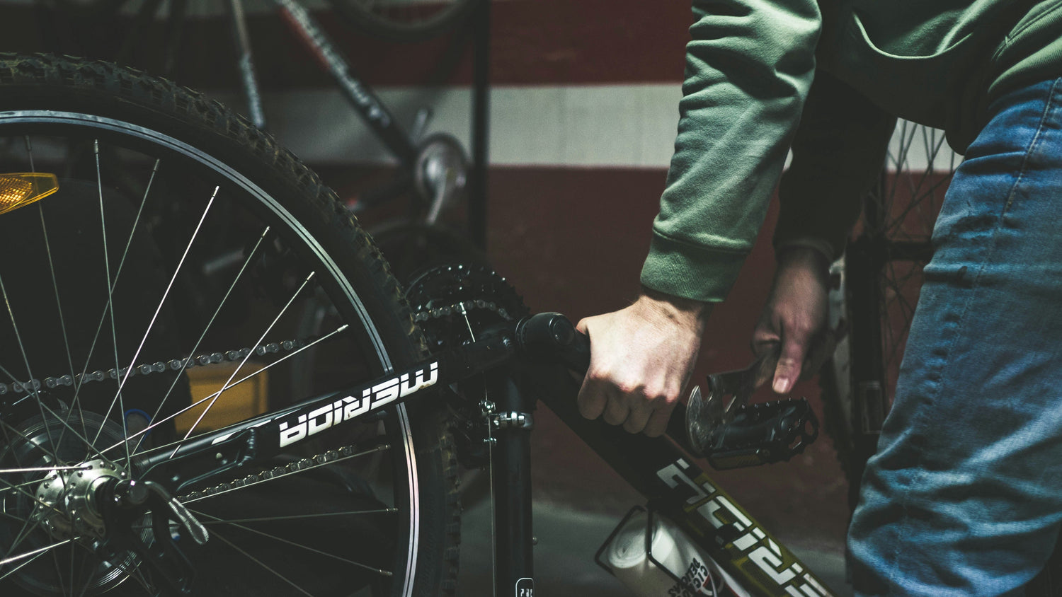 Cyclist adjusting pedals on a mountain bike in a local bike shop workshop.