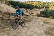 Cyclist riding a gravel bike on an off-road trail through the countryside, showcasing the versatility and adventure-ready design of modern gravel bikes – find yours at MyNextBike.co.uk. 