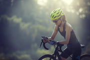 Woman wearing green helmet sat on road bike using her phone -- find your next premium bike for less with MyNextBike.co.uk