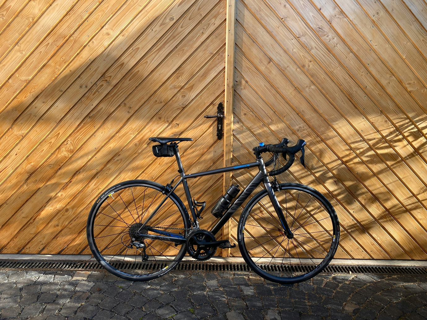 Modern road bike against a wooden backdrop in an urban setting, representing cycling lifestyle, road cycling, bike ownership, and premium performance bicycles