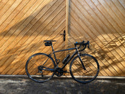 Modern road bike against a wooden backdrop in an urban setting, representing cycling lifestyle, road cycling, bike ownership, and premium performance bicycles
