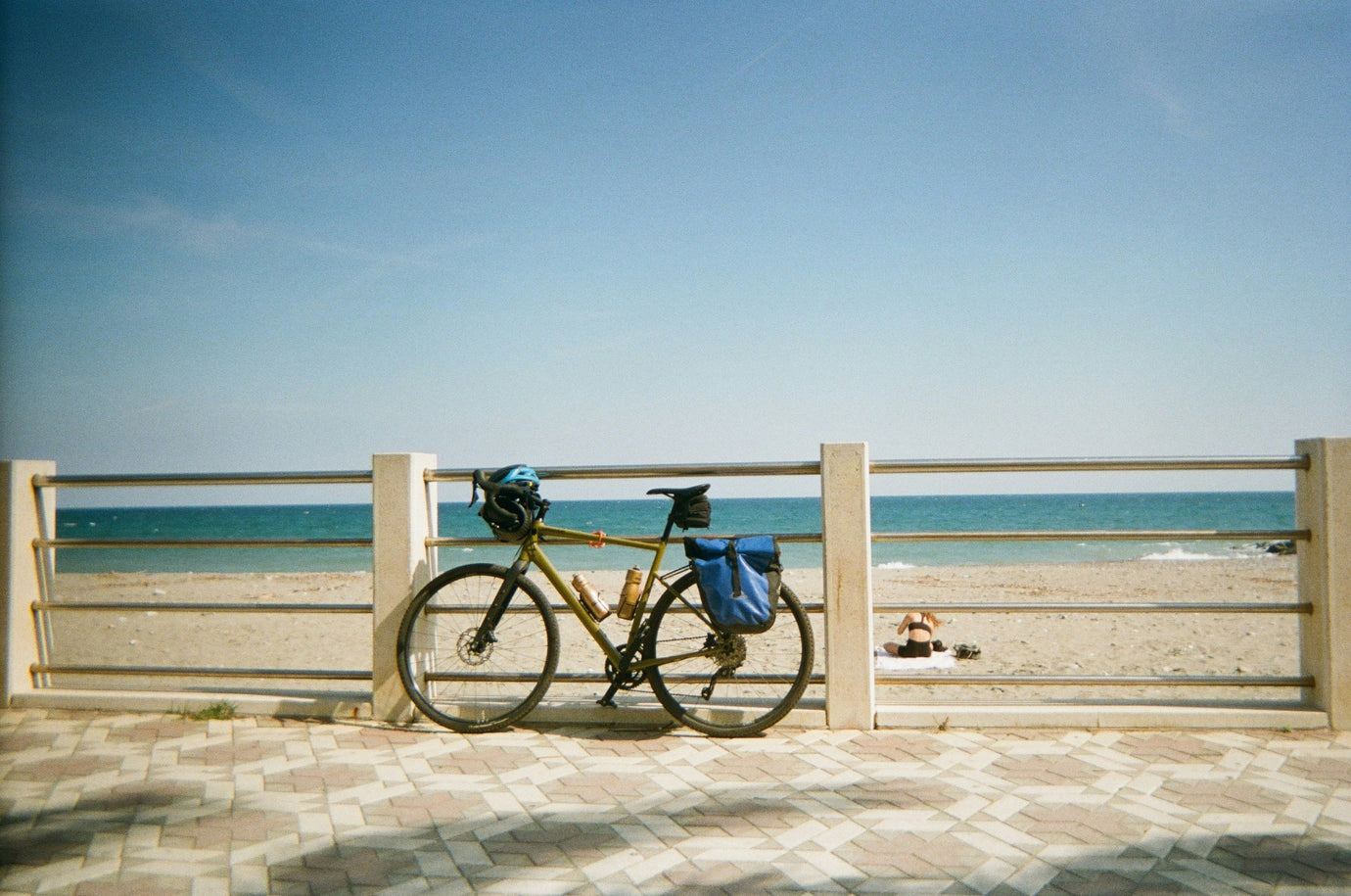 Bike on promenade against railing with bright beach in the background. 