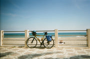 Bike on promenade against railing with bright beach in the background. 