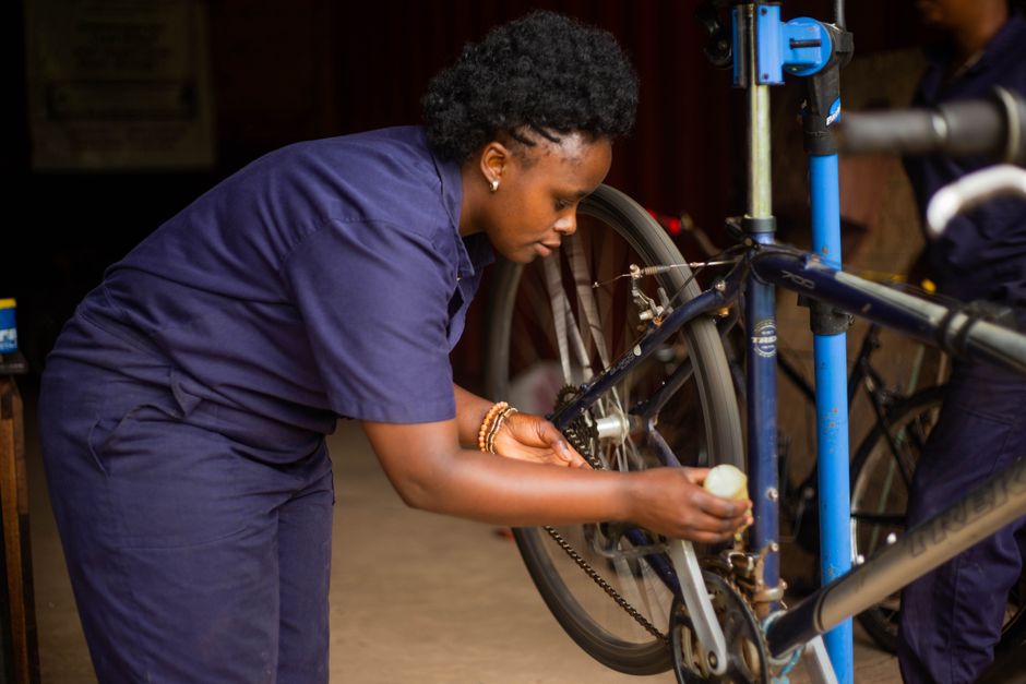 Adult female mechanic meticulously repairing a bicycle in a workshop setting.