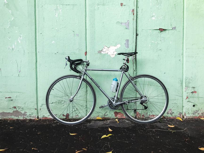 A sleek road bike with a water bottle leans against a pastel green wall, showcasing urban cycling culture in Istanbul.