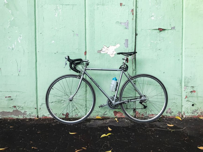 A sleek road bike with a water bottle leans against a pastel green wall, showcasing urban cycling culture in Istanbul.