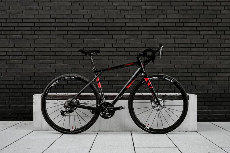 Sleek black and red road bike leaning on a modern brick wall.